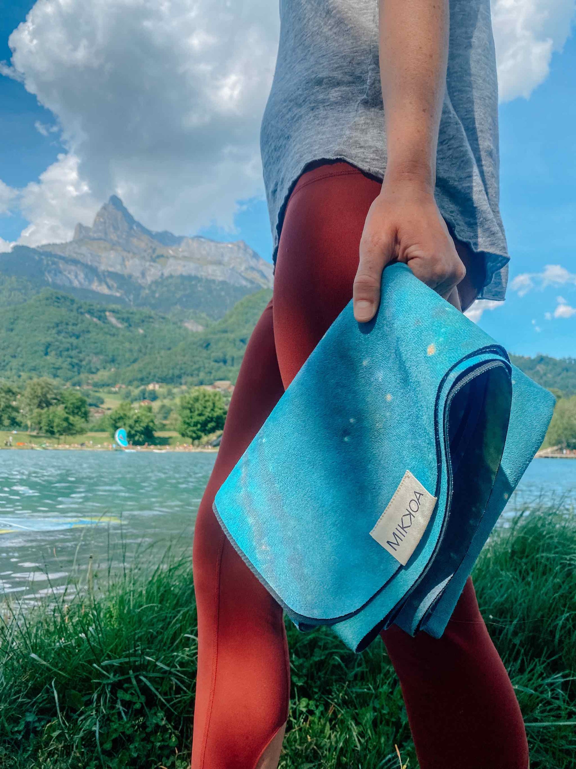 Packable Travel Yoga Mat-Women Holding Folded Yoga Mat Near River-Mikkoa Galaxy Aurora Travel Yoga Mat